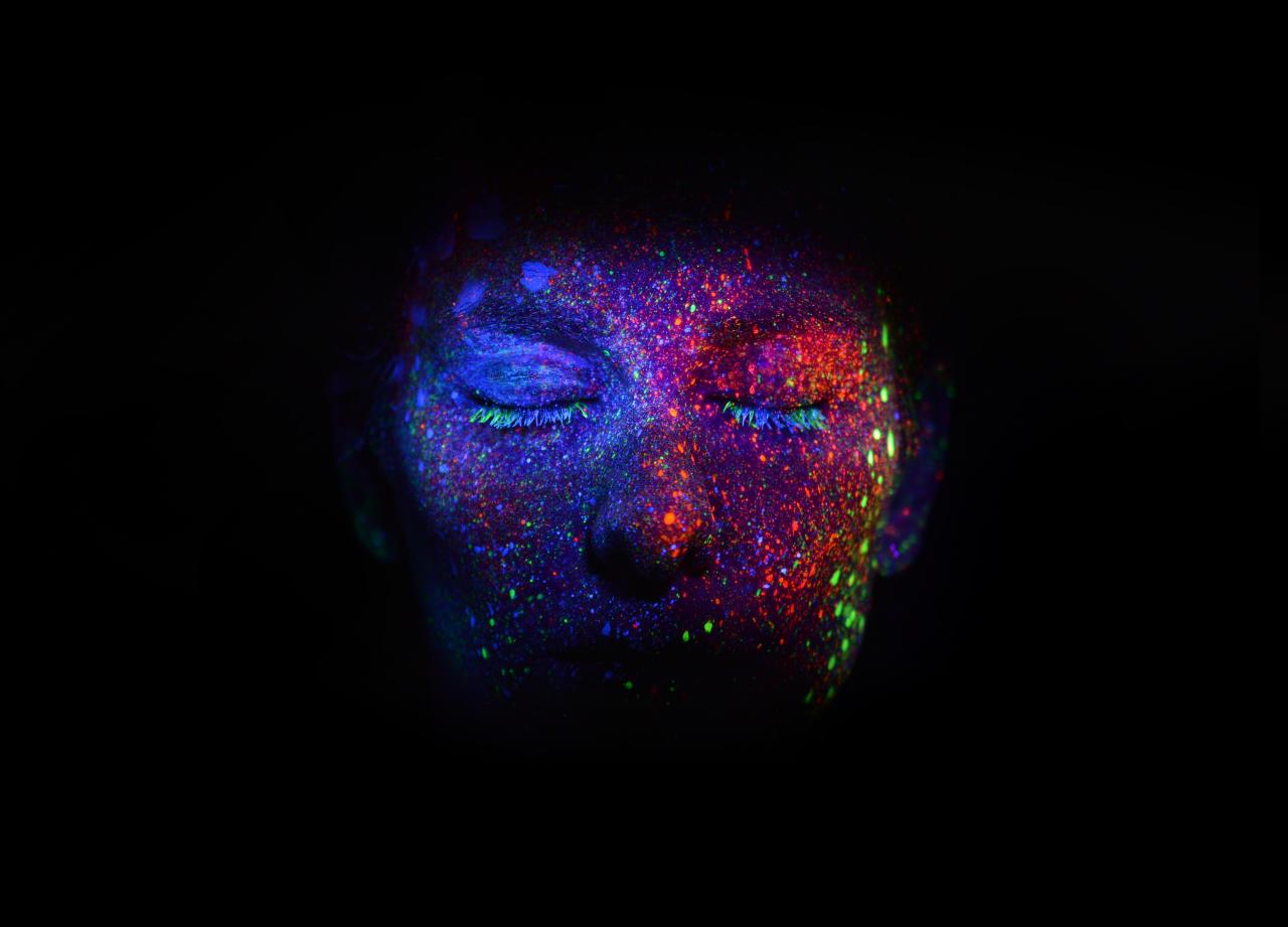 Blacklight and colored dots illuminate a face